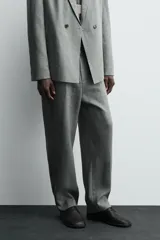 Pantalón de corte straight relaxed fit confeccionado en tejido de lino. Presenta cintura con pliegues frontales, cierre frontal con cremallera y botón, bolsillos laterales y bolsillos traseros con solapa.