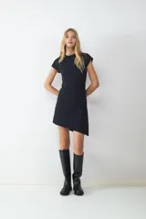 Vestido corto negro de manga corta con detalle cut out en el hombro, silueta recta y dobladillo asimétrico.