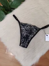 Microtanga de encaje negro con diseño floral en blanco, con tiras finas ajustables en los laterales.