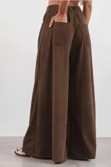 Pantalón de corte ancho confeccionado en corderoy color chocolate, con cintura alta, pasacintos y cierre frontal con botón.