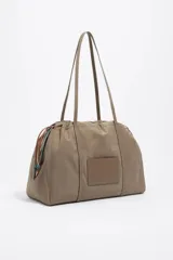 Bolso de hombro de tamaño grande confeccionado en nylon, con estructura blanda y diseño funcional. Presenta dos asas de tejido y cierre con cremallera que permite ajustar su capacidad, además de bolsillo interior para una mejor organización. El logo grabado y la placa interior aportan un detalle distintivo de la marca.