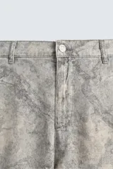 Pantalón de corte relajado confeccionado en tejido ligero de algodón con estampado abstracto de efecto lavado. Presenta cintura elástica, bolsillos frontales y bolsillos traseros de plastrón, con cierre frontal de cremallera y botón.