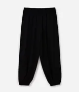 Pantalón de corte aladín confeccionado en crepé, de tiro alto con cintura elástica en la parte trasera. Presenta piernas anchas con volumen tipo globo que se estrechan en los tobillos mediante puños elásticos. Incluye bolsillos laterales funcionales.