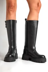 Borcegos negros de ecocuero con caña alta y base con plataforma. Presentan correas con hebillas plateadas en la parte superior y alrededor del tobillo.