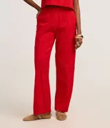 Pantalón recto de cintura alta confeccionado en tejido laise de algodón color rojo, con diseño de perforaciones y cierre lateral con cremallera.