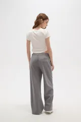 Pantalon de corte holgado y tiro alto, confeccionado en tejido de punto gris con costuras frontales verticales que simulan una tabla.
