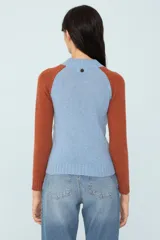 Sweater bicolor de tejido de punto, con mangas ranglán color ladrillo y cuerpo celeste con diseño de trenzas.