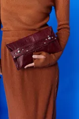 Sobre de cuero negro con solapa, cierre magnético y muñequera con tachas plateadas.