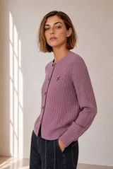 Cardigan de punto con diseño de ochos y canalé, color lila, con cuello redondo, manga larga y cierre frontal de botones. Cuenta con detalle de logo bordado en el pecho.