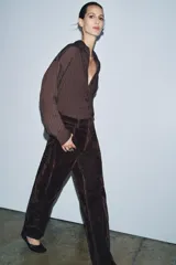 Jeans de tiro alto con corte balloon leg y largo completo. Presentan diseño de cinco bolsillos, trabillas en la cintura y cierre frontal con cremallera y botón. Confeccionados en tejido flocado con textura aterciopelada.