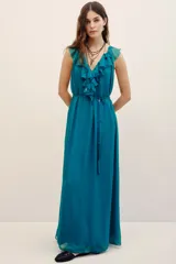 Vestido largo color verde turquesa, confeccionado en gasa con forrería a tono. Posee escote en V profundo con volados, sin mangas, y corte en la cintura con lazo ajustable.