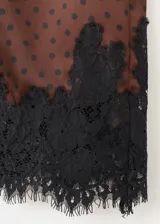 Minifalda marrón satinada con estampado de lunares negros y detalle de puntilla de encaje negro en el ruedo.
