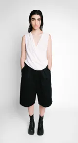 Blusa blanca sin mangas con escote en V cruzado y drapeado.