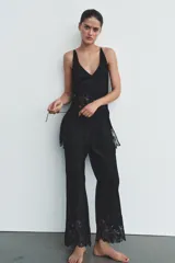 Pantalón de tiro alto confeccionado en viscosa, con cintura elástica ajustable mediante cordones. Presenta un diseño de corte recto y fluido, con el bajo decorado con encaje y bordados a tono.