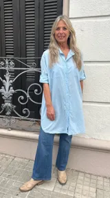 Camisa celeste de fibrana con dos bolsillos frontales y mangas 3/4 con botón para sujetar.