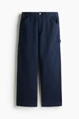 Pantalón tipo worker confeccionado en sarga de algodón de color azul marino, con un corte relaxed fit y piernas rectas. Presenta una cintura clásica con cierre de botón, bolsillos laterales al bies, bolsillos traseros, una trabilla funcional en un lateral y un bolsillo cargo dividido en el otro.