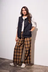 Chaleco oversize de denim negro con costuras en hilo ocre, cuello camisero, cierre frontal con botones y bolsillos delanteros.