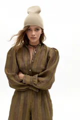 Camisa de lino con estampado de rayas verticales en tonos tierra. Presenta cuello camisero clásico, cierre frontal con botones de nácar, mangas largas abullonadas y puños con terminación ondulada.