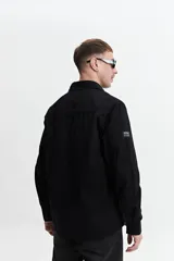 Sobrecamisa verde militar de twill de algodón, con cuello clásico, cierre frontal con botones a tono, dos bolsillos tipo parche con solapa abotonada en el pecho, mangas largas con puños abotonados y corte recto.