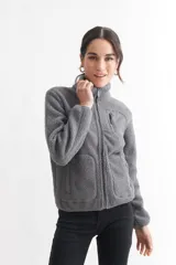 Campera negra de corderito con cuello alto, cierre frontal con cremallera, bolsillo de parche en el pecho y bolsillos laterales.