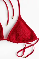 Top de bikini triangular rojo con textura estilo crochet, copas con relleno extraíble y tiras para atar en el cuello y la espalda.