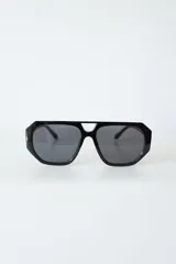 Lentes de sol con armazón de policarbonato negro y cristales tonalidad ámbar, con diseño de puente doble estilo aviador.