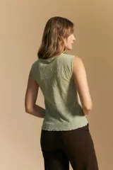 Top sin mangas de jacquard color negro, con cuello cerrado y silueta recta. Presenta una textura trabajada con relieve y una terminación suavemente ondulada en el ruedo.