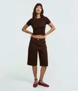 Blusa cropped de manga corta y cuello redondo, confeccionada en tejido rib acanalado de color marrón oscuro.