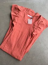 Vestido largo de algodón tusor en color blanco, con volados en las sisas que simulan mangas y aberturas laterales en la falda.