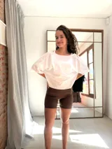 Remera corta de manga corta color celeste, con escote amplio en la espalda que se anuda en la parte inferior, dejando ver un top deportivo amarillo con tiras cruzadas.