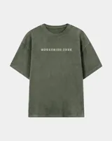 Remera oversize verde militar con efecto acid wash, cuello redondo y estampa frontal con la inscripción "WORLDWIDE TOUR" en tipografía gótica.