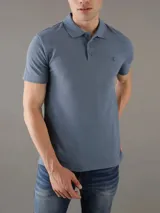 Chomba de piqué azul con cuello polo y tapeta de tres botones. Tiene mangas cortas, corte relaxed y logo de Calvin Klein bordado en el pecho. Confeccionada en algodón.
