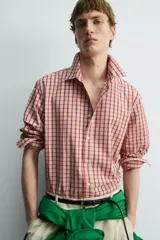 Camisa de algodón con cuello solapa, manga larga terminada en puño con botón y cierre frontal de botonadura. Presenta un patrón de cuadros en tonos rojo y beige.