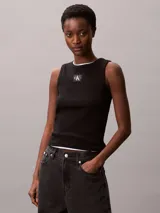 Musculosa Calvin Klein de corte slim confeccionada en tejido de canalé de algodón con elastano. Presenta cuello redondo, tirantes anchos y una etiqueta con el monograma CK en el centro del pecho.