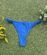 Bikini de dos piezas color azul vibrante. El corpiño es tipo top con un detalle de hebilla redonda dorada en el centro. La bombacha es colaless entera con frunces ajustables en los laterales.