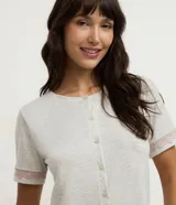 Pijama capri de viscolycra color gris melange, compuesto por una remera de manga corta con botonadura frontal y un pantalón capri. Ambas prendas cuentan con detalles de encaje rosado en las terminaciones.