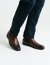 Bota tipo Chelsea de cuero negro con paneles elásticos laterales, suela de goma con detalle de vira en contraste y tirador trasero.