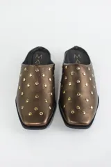 Zueco de cuero color bronce con punta almendrada y detalle de tachas metálicas doradas en toda la capellada. Posee un taco cuadrado bajo de 3 cm.