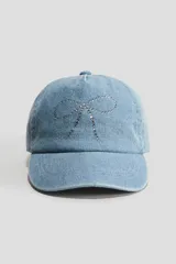 Gorra de sarga de algodón tipo denim azul claro, con diseño de lazo formado por pedrería de strass en la parte frontal.