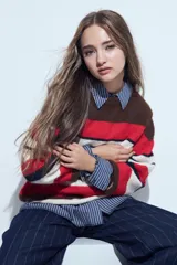 Sweater de tejido de punto con diseño de rayas horizontales en tonos rojo, blanco, azul marino y marrón. Presenta cuello redondo, mangas largas y un calce relajado.