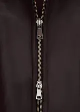 Campera de cuero de ovino en color marrón oscuro, de diseño amplio con cuello solapa grande y cierre frontal con cremallera.