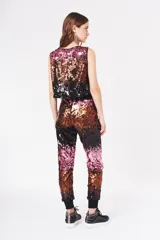 Babucha de poliéster con lentejuelas en degradado de colores: negro, dorado y rosado. Tiene forro interior y puños elásticos en los tobillos.