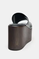 Sandalia tipo mule de plataforma alta, color negro, con tira ancha delantera de cuero y suela plataforma gruesa con acabado de madera oscura.