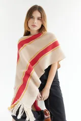 Ruana artesanal de tejido de punto, color beige con franjas horizontales gruesas rojas y finas amarillas. Posee flecos en el borde inferior.