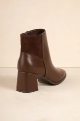 Botas de caña baja color negro, de símil cuero con punta redonda, cierre lateral, taco cuadrado y recorte en gamuza en la parte trasera.