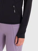 Chaqueta deportiva negra con cierre frontal completo, cuello alto y bolsillos laterales con cierre. Presenta mangas largas con aberturas para los pulgares y logo reflectante en el pecho.
