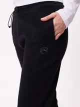 Pantalón tipo babucha de algodón y poliéster, con cintura elástica ajustable mediante cordón, bolsillos laterales y puños elásticos en los tobillos. Presenta un pequeño logo bordado en la pierna izquierda.