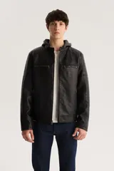 Campera de cuero sintético negra con capucha de algodón gris, cierre frontal con cremallera, bolsillos laterales con cremallera y detalles acolchados en hombros y mangas.