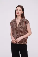 Blusa sin mangas de corte holgado, confeccionada en tela de viscosa con estampado de rayas verticales en tonos mostaza y blanco. Presenta cuello en V profundo y detalles bordados en los hombros.