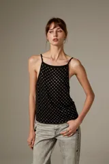 Top halter negro de viscosa, sin mangas, con tirantes finos y cobertura completa de ojalillos metálicos plateados.